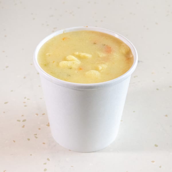 Creamy potato soup with visible chunks of potatoes and vegetables in a white cup.